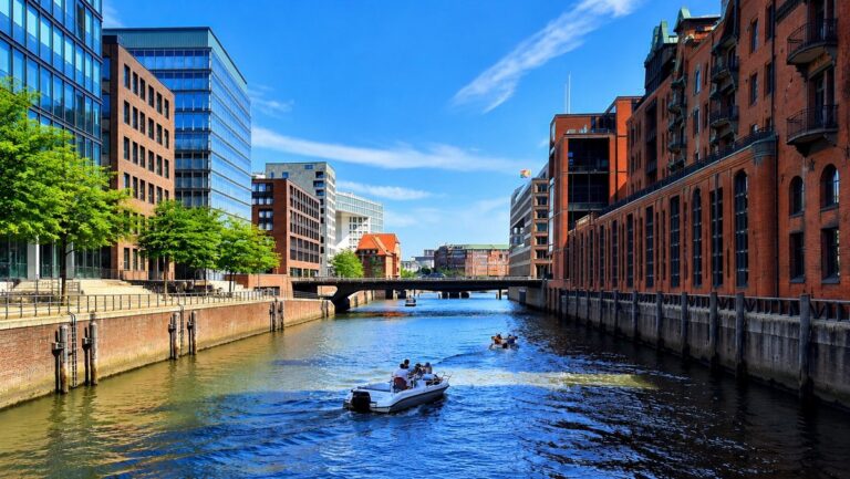 View along a Hamburg canal with historic red-brick warehouses and a boat on the wate