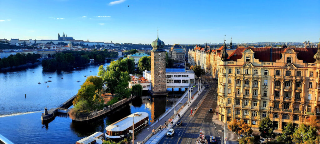 Panoramic view of the Vltava River, Prague Castle and historic waterfront buildings from the Dancing House rooftop.