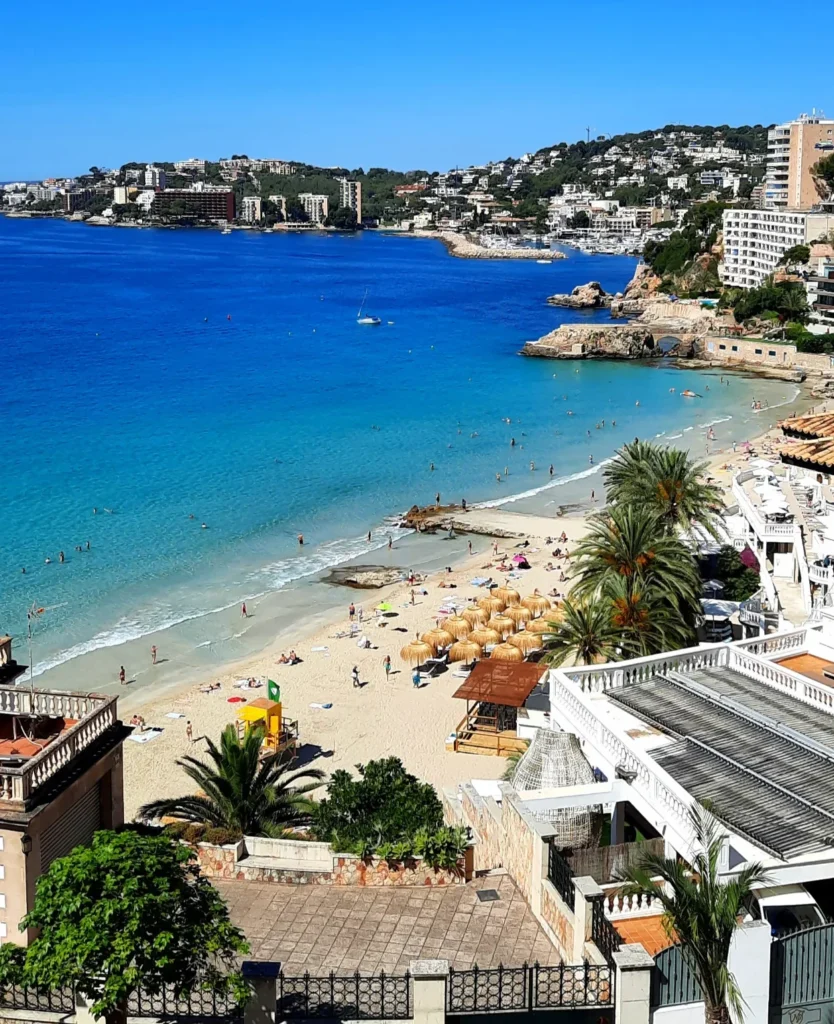 View of Cala Major beach in Mallorca with turquoise water, sun loungers and straw parasols