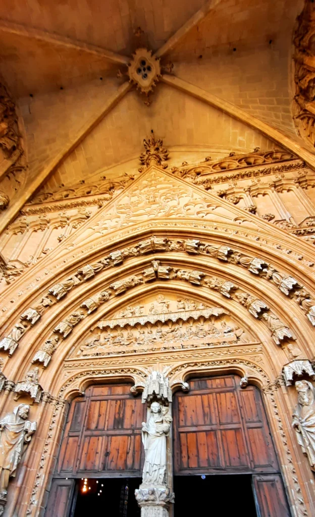 Ornately carved Gothic stone entrance and wooden doors of Palma Cathedral in Mallorca